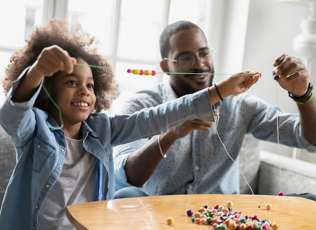 Personal Insurance - Father and Daughter Making Bead Necklaces Together at Home
